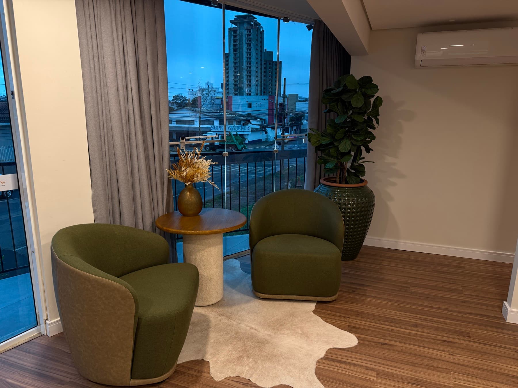 Espaço de espera com poltronas verdes e vista